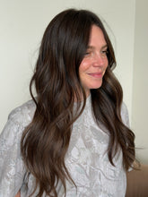 Load image into Gallery viewer, Woman with long, wavy hair lying on a white surface